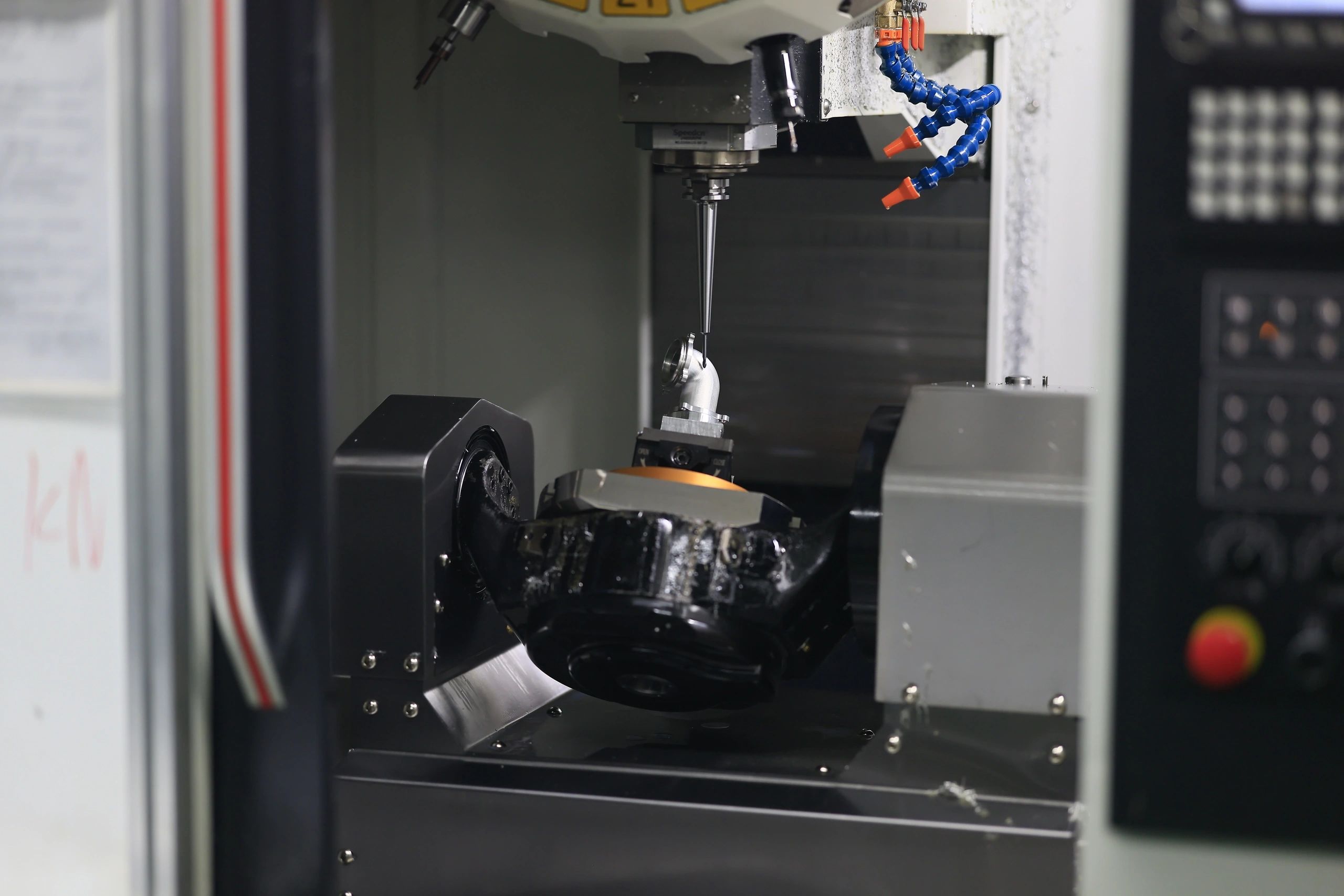5-axis machined aluminium elbow fitting on a tilting rotary table